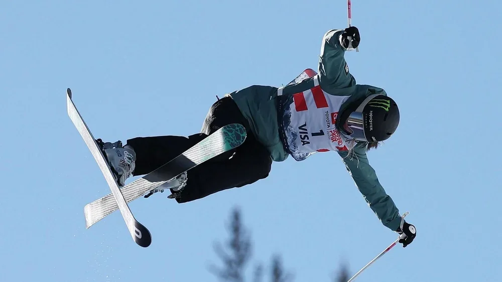 Zoe Atkin off the ground on her skis, which cross as she hangs in the air